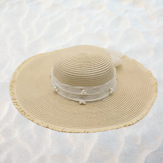 Beige straw hat with a decorative band on a sandy background