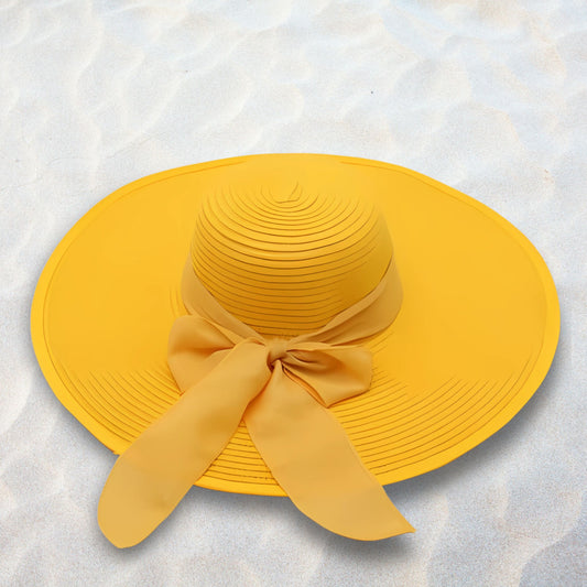 Yellow sun hat with a bow on a textured white background