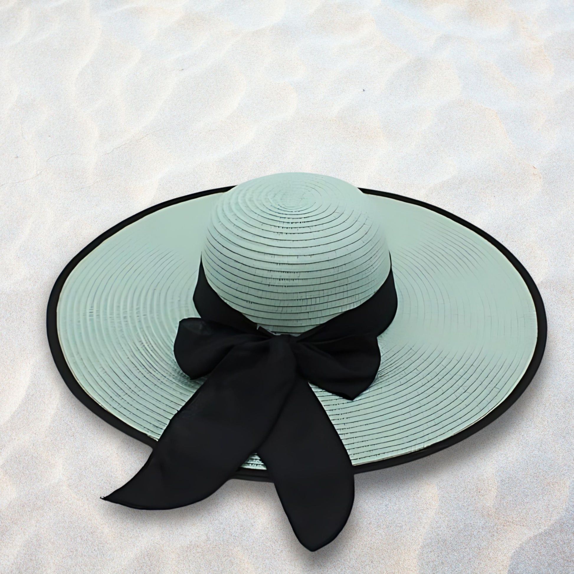 Mint green sun hat with a black ribbon on a light stone background