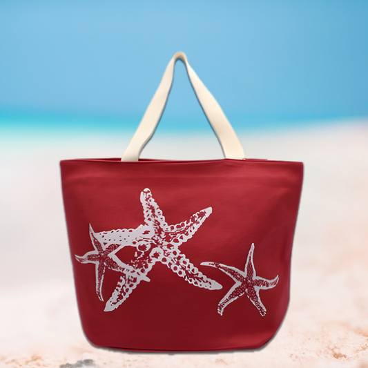Red tote bag with white starfish designs on a beach setting