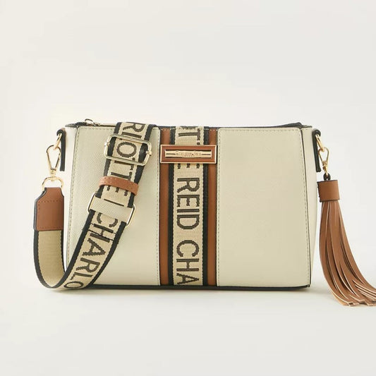 Beige pouch crossbody bag with removable and adjustable woven textured strap, with a monogram strip and removable tassel.