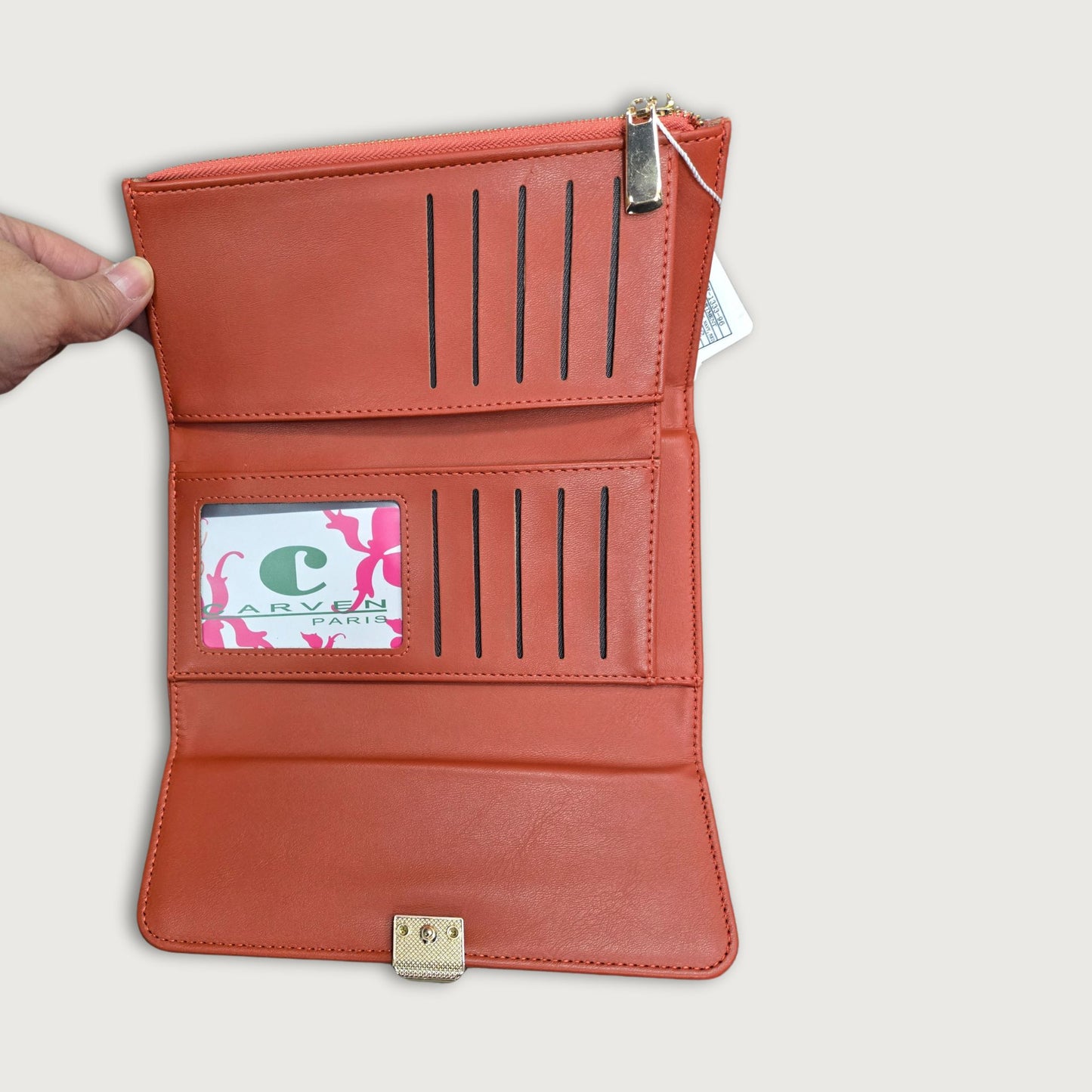 A red faux leather trifold wallet with a main compartment and multiple card slots, featuring a round emboss design on the clasp and gold hardware.