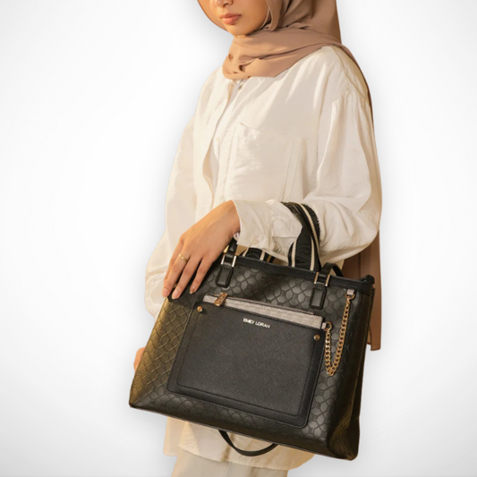 Person holding a black handbag with gold accents on a white background