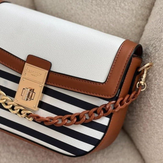 Designer handbag with white body, brown leather strap, and black and white striped pattern.