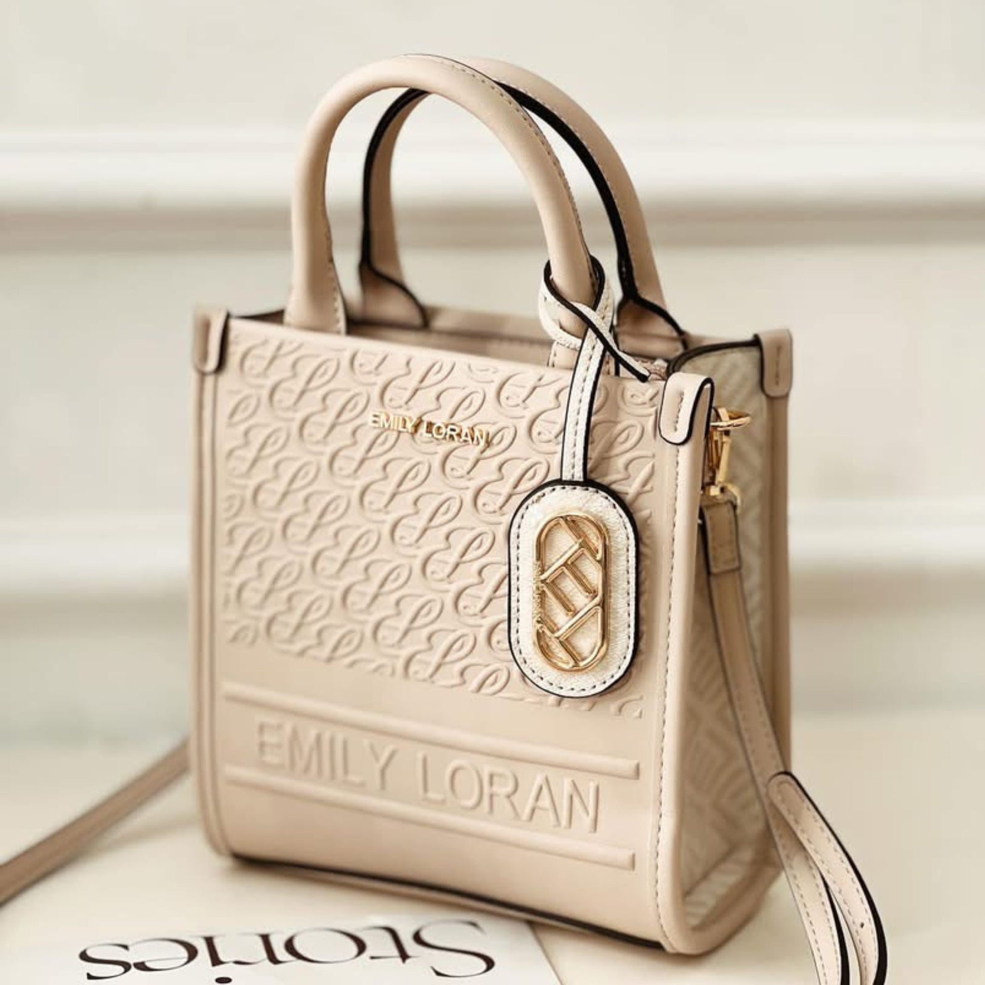 Beige handbag with 'EMILY LORAN' branding on a light background