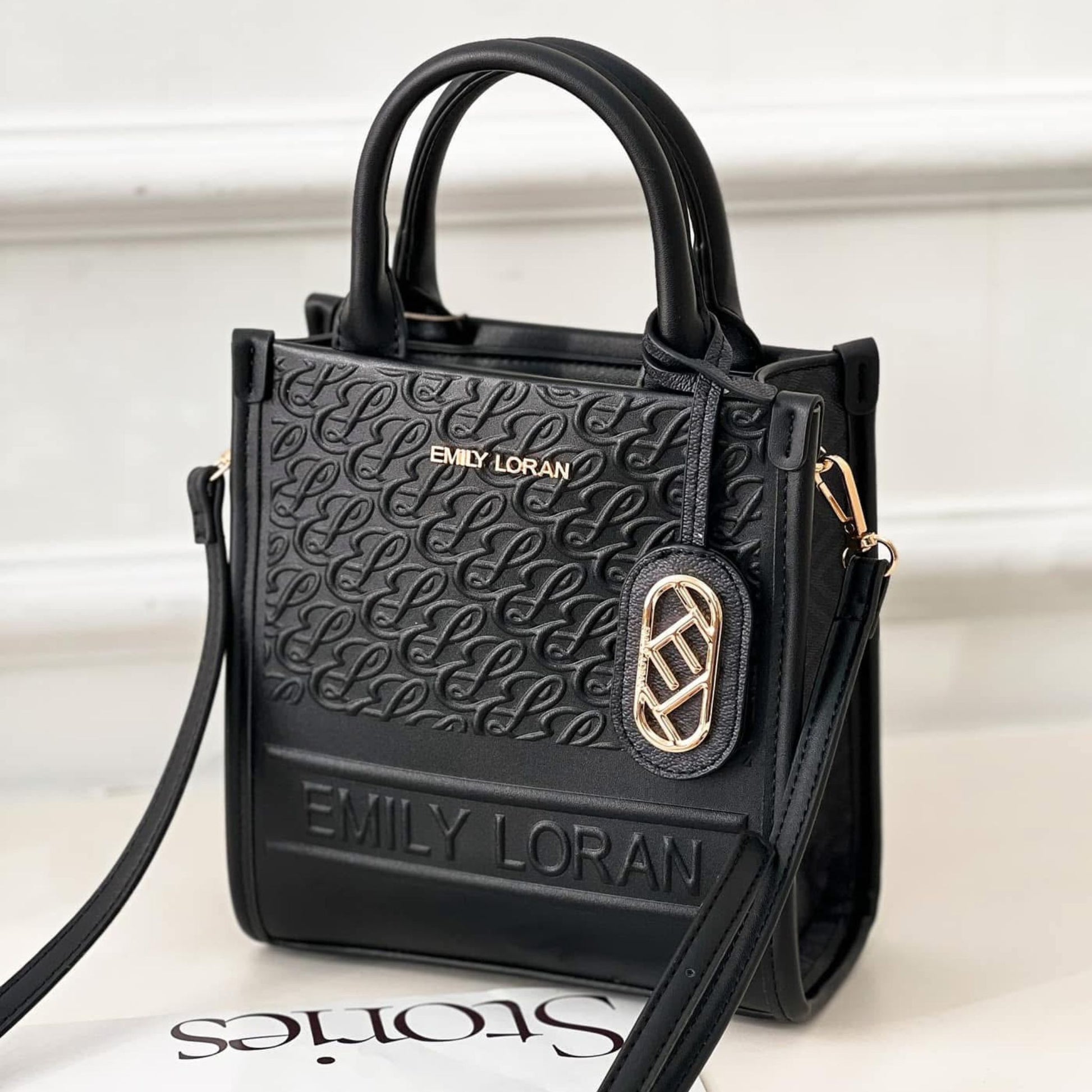 Black handbag with gold accents and 'EMILY LORAN' branding on a white background