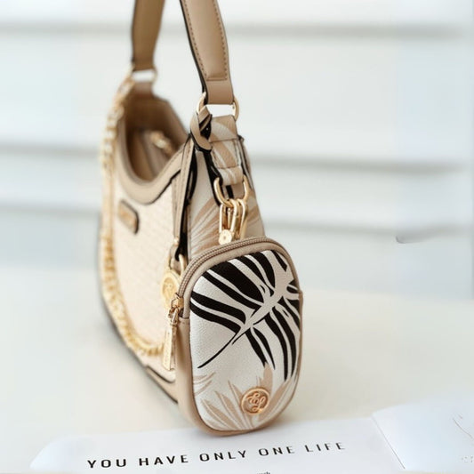 Beige handbag with black leaf pattern on a white surface