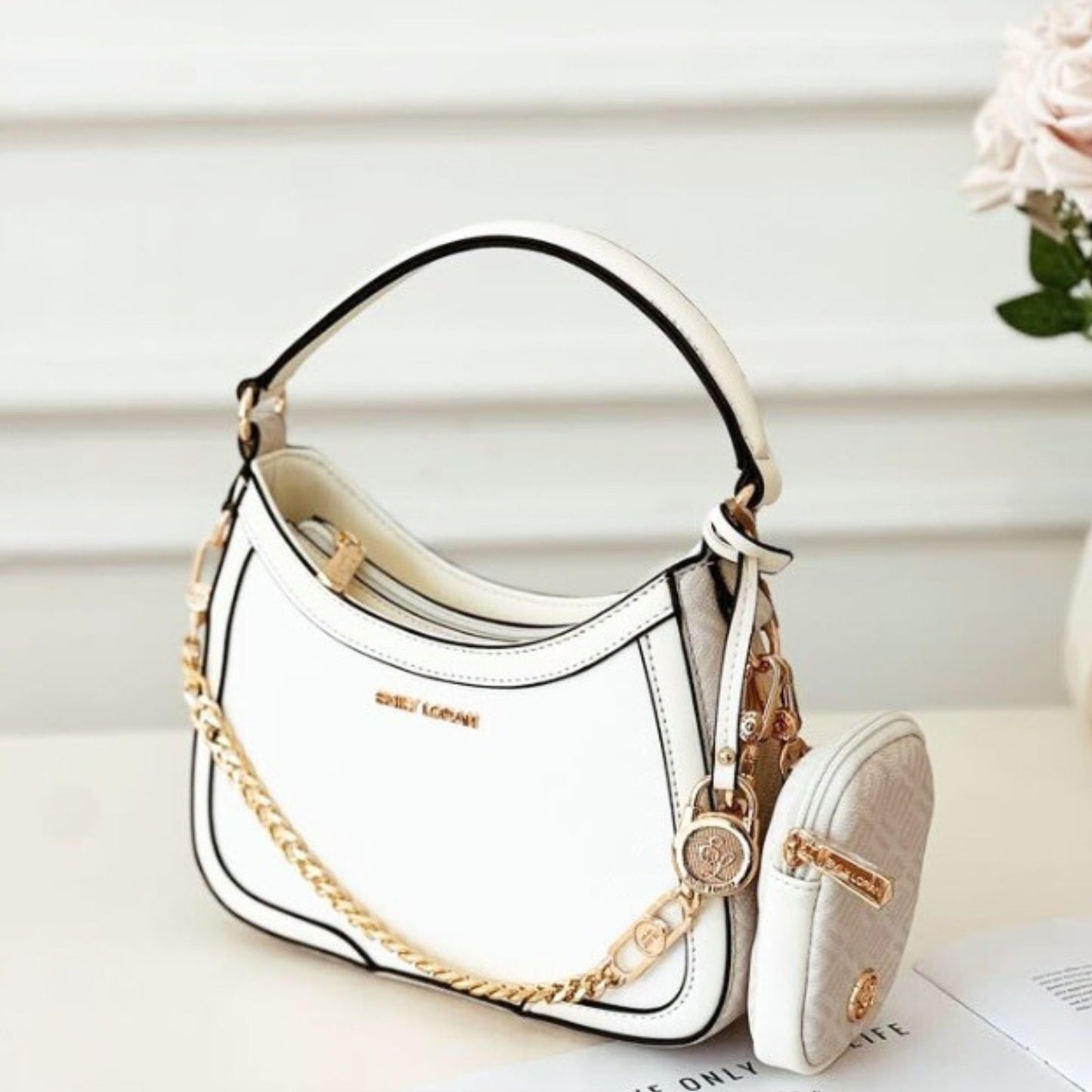 White handbag with gold chain detail on a light background