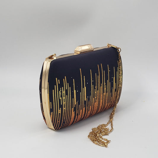 Black clutch with gold and bronze gradient pattern on a light background
