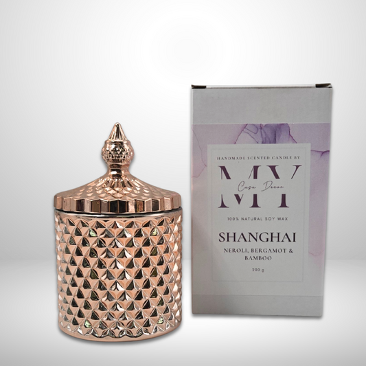 Rose Gold textured candle jar with decorative lid next to its packaging on a white background