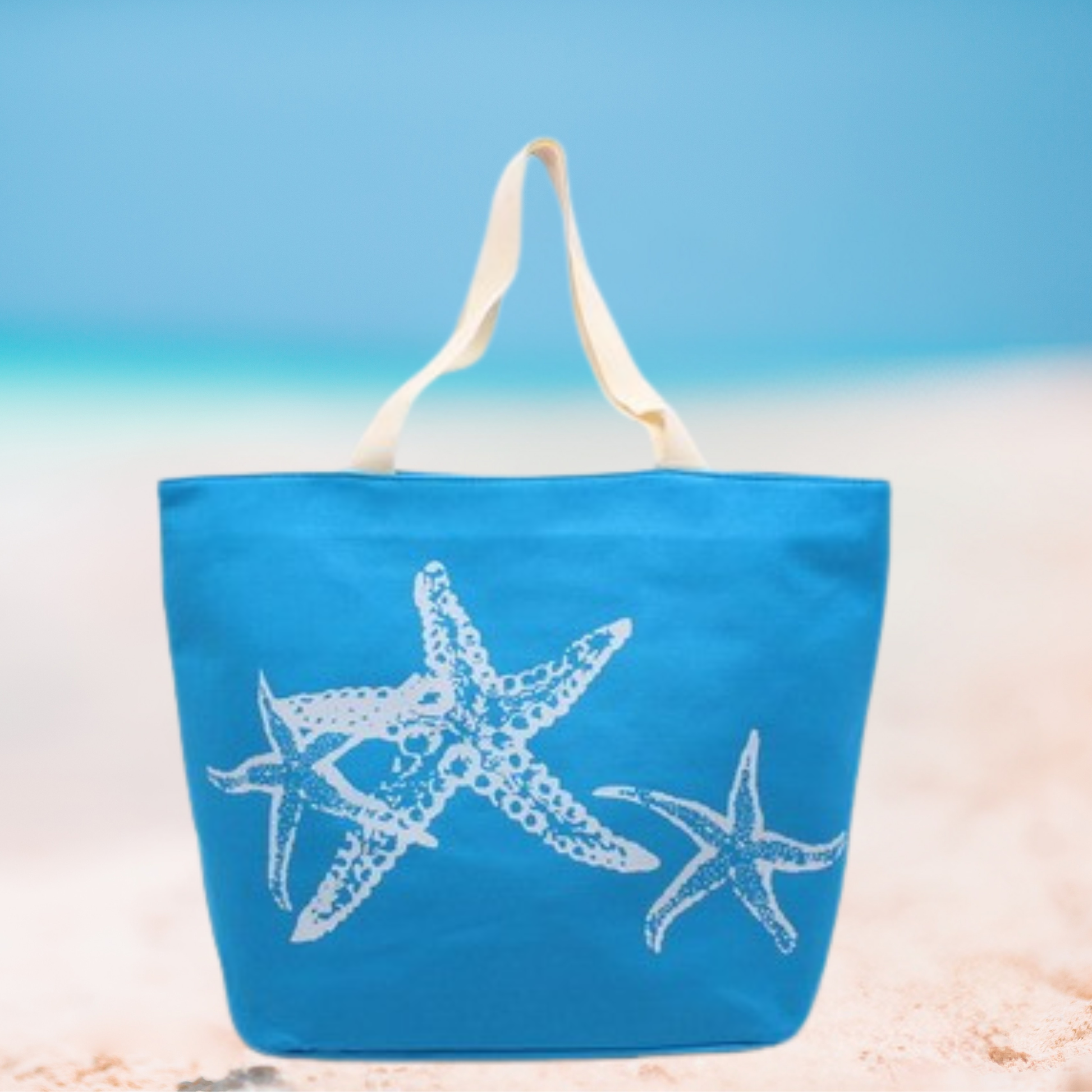 Blue tote bag with white starfish design on a beach setting