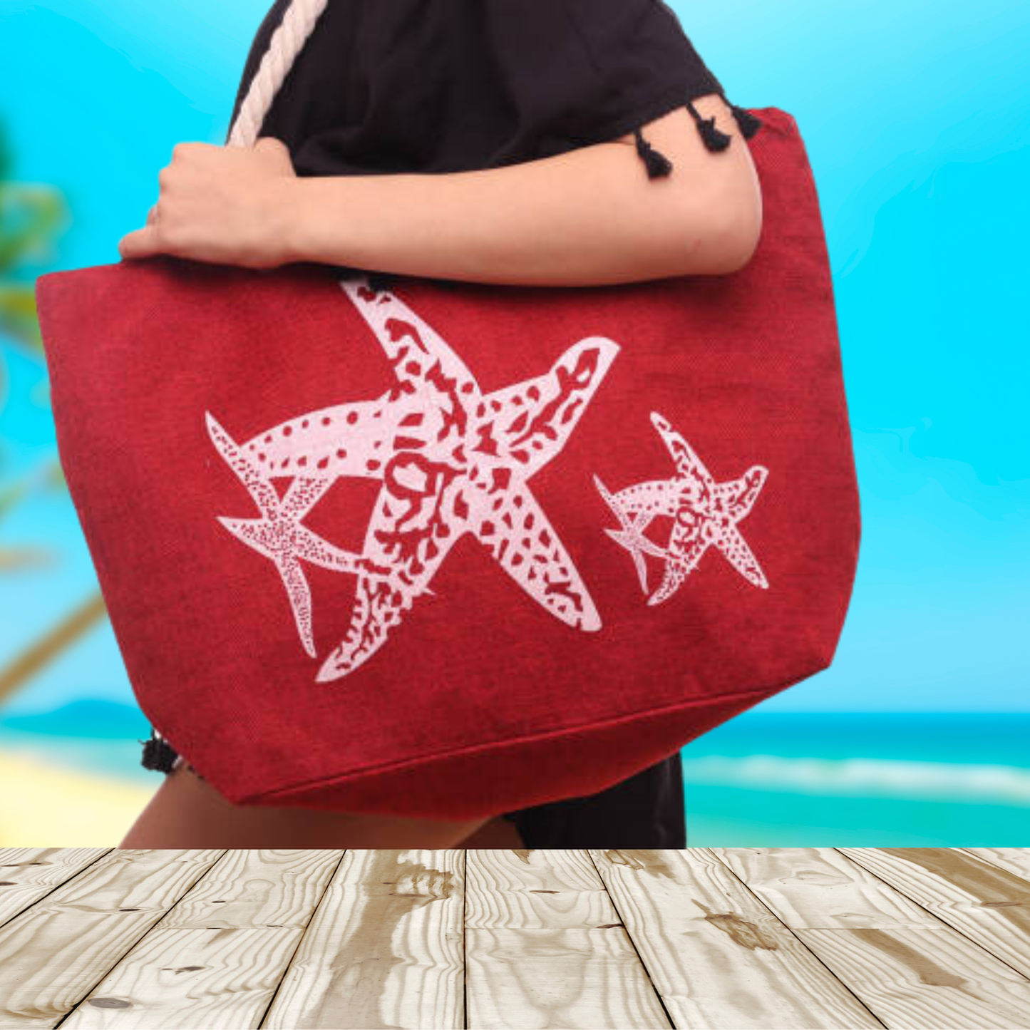 Red tote bag with white starfish design held by a person against a blurred beach background