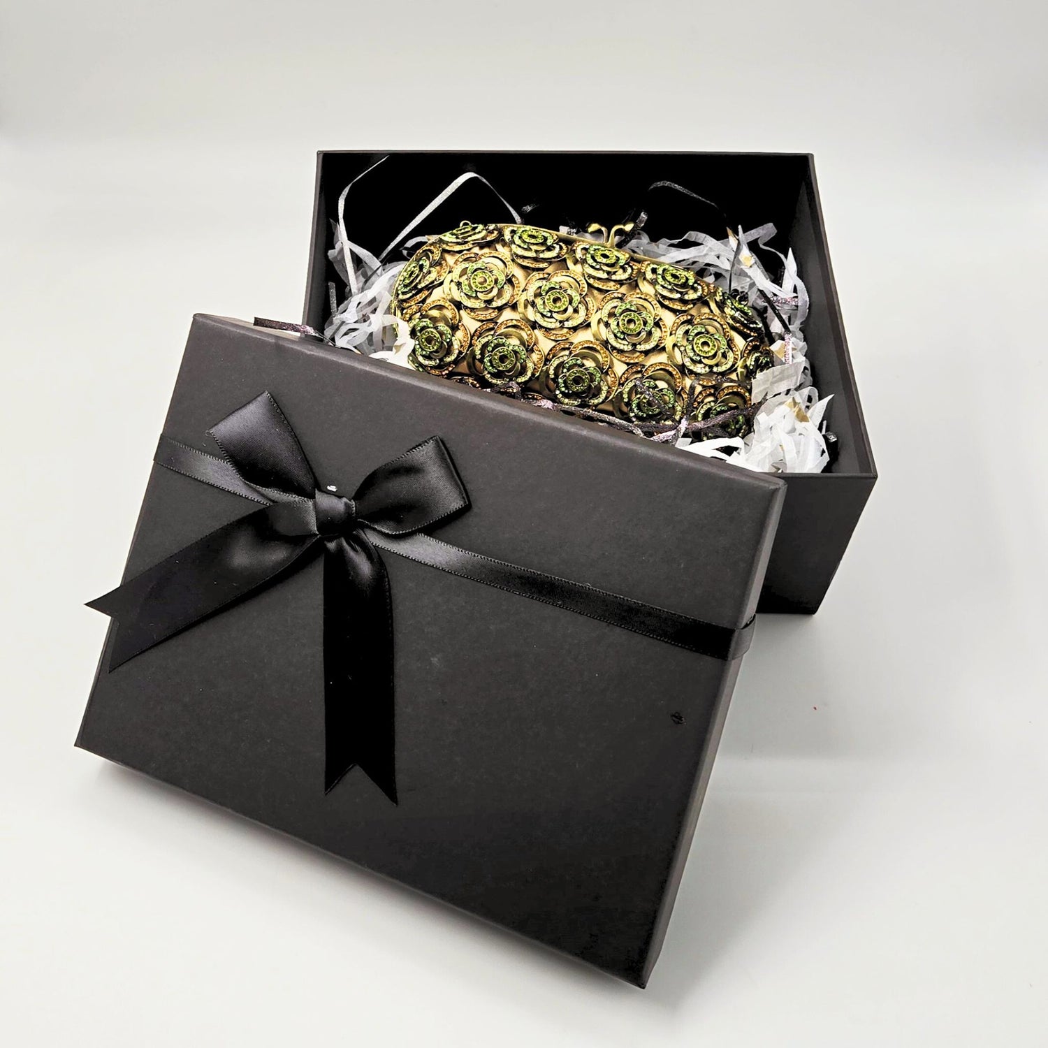 A black gift box with a decorative paper and ribbon, closed with a bow.
