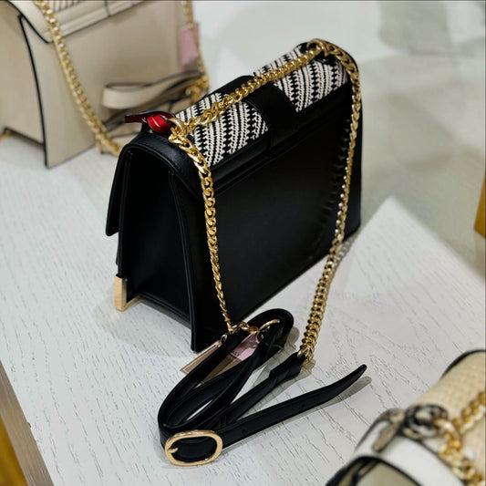 Black handbag with gold chain strap on a light wooden surface from InStyle Fashion Hong Kong.