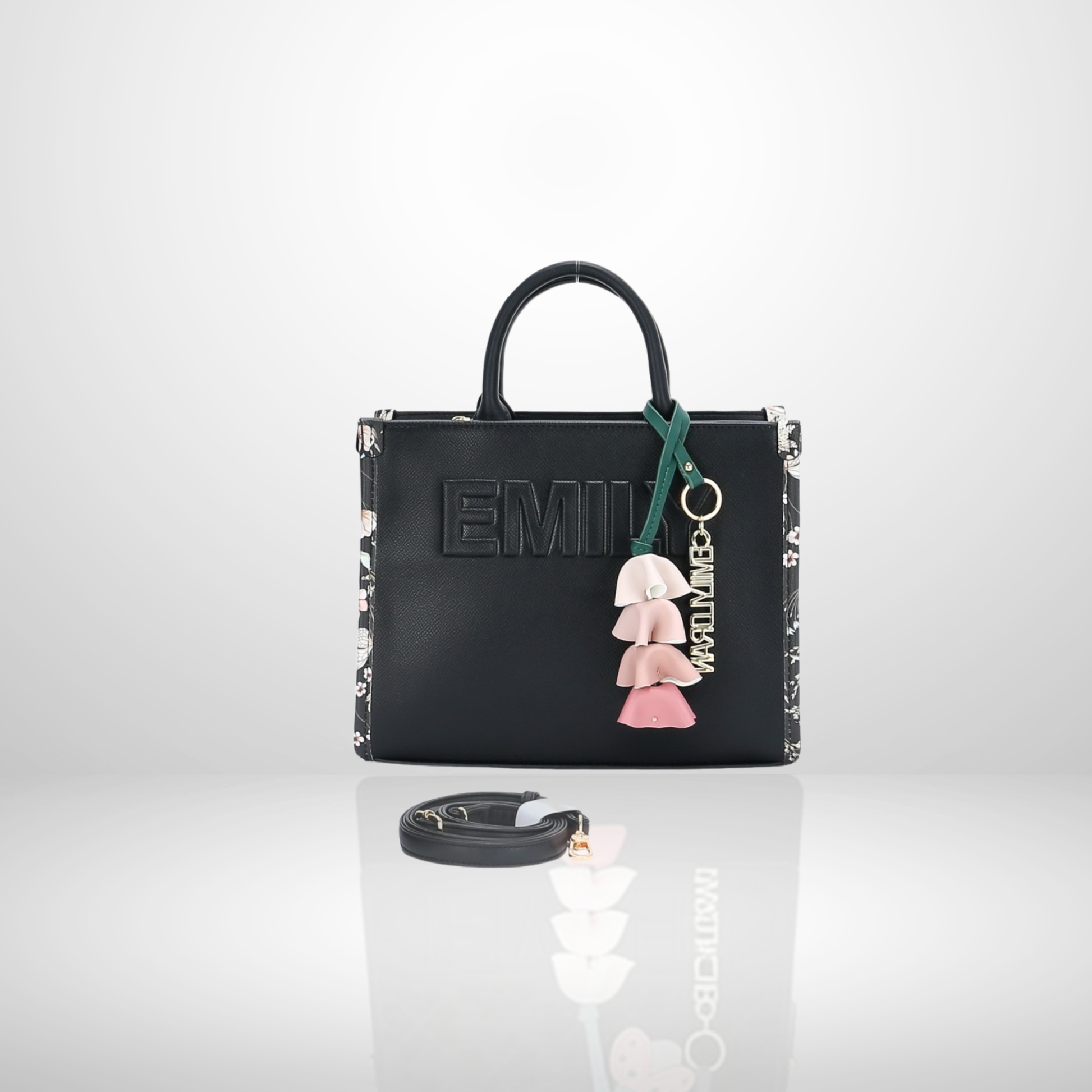 Elegant women's structured tote bag with embossed front logo, floral tassel keychain charm, top handles, and detachable shoulder strap, available in black.