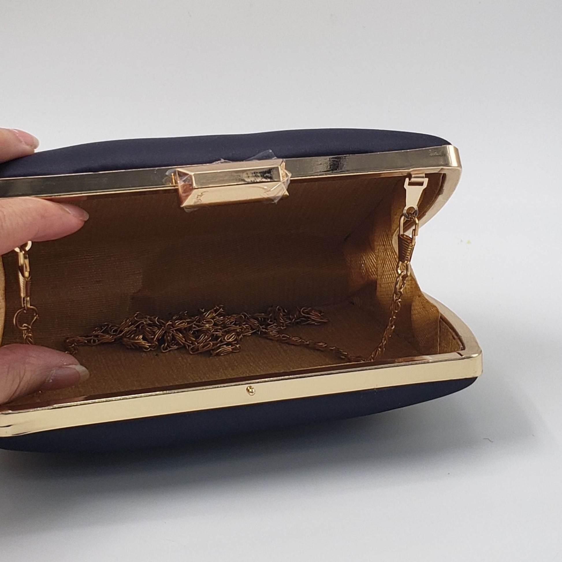 Black clutch with gold and bronze gradient pattern on a light background