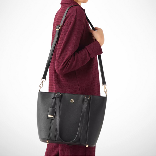 Person wearing a maroon sweater holding a black handbag on a white background
