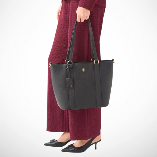 Person holding a black handbag with a plain background